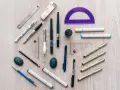 Herramientas de dibujo: reglas, escuadras, transportador, marcadores, bolígrafos y un sacapuntas. ¡Todo listo para crear!