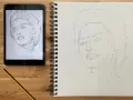 Un boceto a lápiz de un retrato en una tableta inspira un nuevo dibujo en un cuaderno. Aprende como dibujar un retrato observando los pasos.