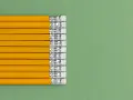 Una fila de lapiceros o portaminas amarillos con gomas de borrar blancas sobre un fondo verde.