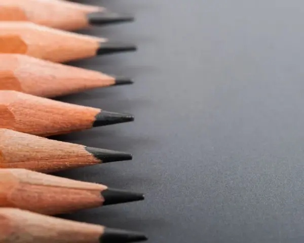 Filas de lápices de madera con puntas afiladas, listos para dibujar. La dureza de los lápices varía, ofreciendo distintas tonalidades.