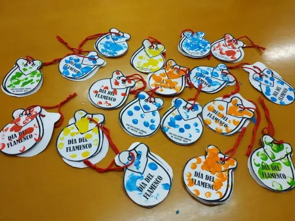 Manualidades flamencas para niños: castañuelas de papel con huellas dactilares de colores, decoradas para el Día del Flamenco.