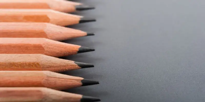Filas de lápices de madera con puntas afiladas, listos para dibujar. La dureza de los lápices varía, ofreciendo distintas tonalidades.